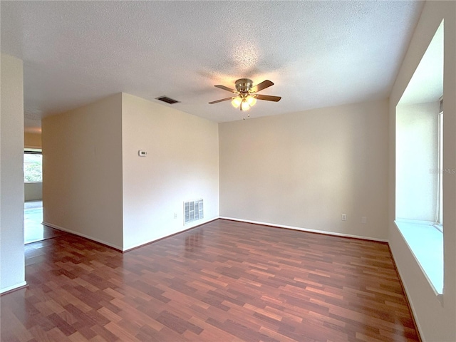 spare room featuring ceiling fan, visible vents, a textured ceiling, and wood finished floors