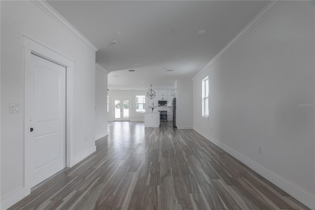 unfurnished living room with crown molding, baseboards, and wood finished floors