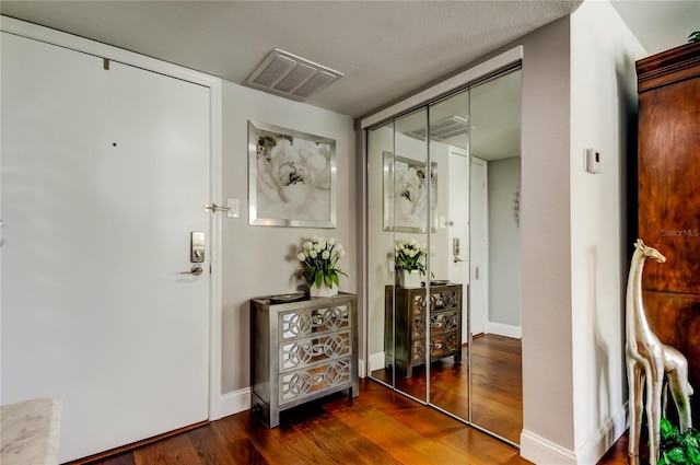 foyer entrance with baseboards, visible vents, and wood finished floors