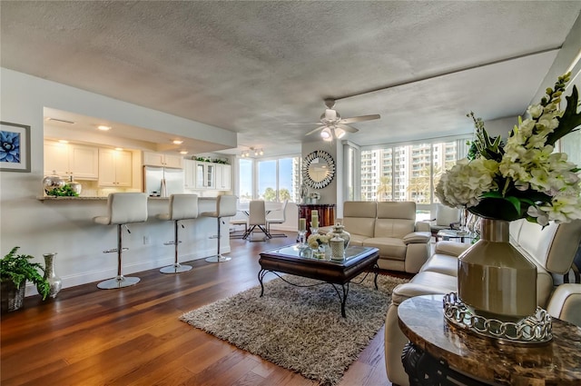 living area with baseboards, a ceiling fan, dark wood-type flooring, a textured ceiling, and recessed lighting