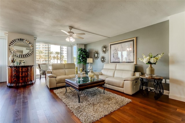 living area with hardwood / wood-style floors, a ceiling fan, a textured ceiling, a wall of windows, and baseboards