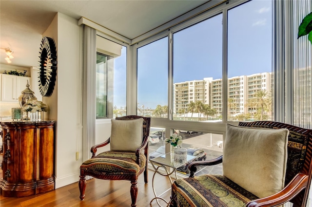 sitting room with baseboards, plenty of natural light, wood finished floors, and floor to ceiling windows