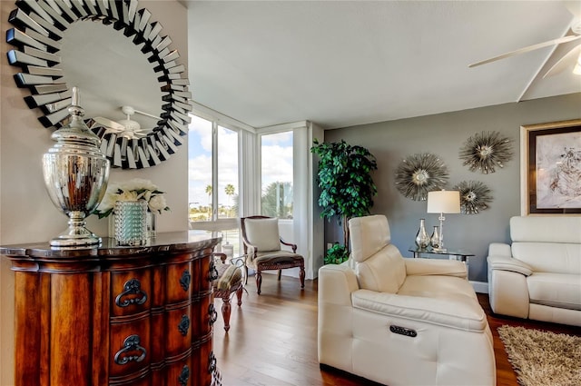 living area featuring a wall of windows, ceiling fan, and wood finished floors