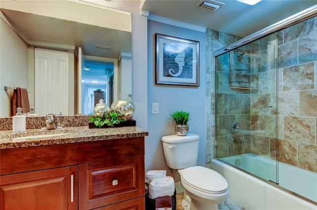 bathroom featuring visible vents, bath / shower combo with glass door, toilet, ornamental molding, and vanity