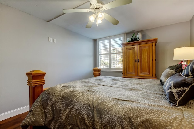 bedroom with dark wood-type flooring, a ceiling fan, and baseboards