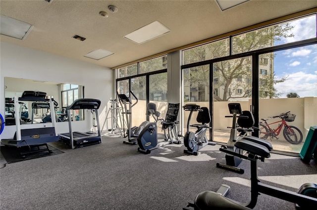 exercise room with a wall of windows, visible vents, and a textured ceiling