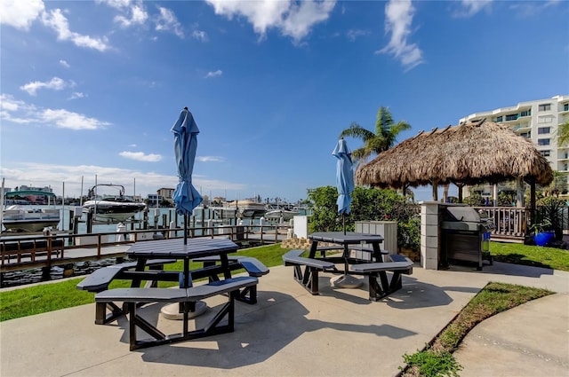 view of home's community featuring a boat dock, boat lift, outdoor dining area, a gazebo, and a patio area