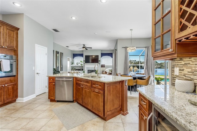 kitchen with stainless steel appliances, visible vents, decorative backsplash, brown cabinetry, and a sink