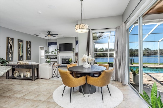 dining room with light tile patterned floors, ceiling fan, visible vents, and a glass covered fireplace