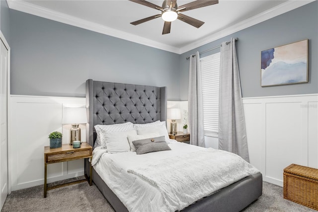 carpeted bedroom featuring ceiling fan, crown molding, and wainscoting