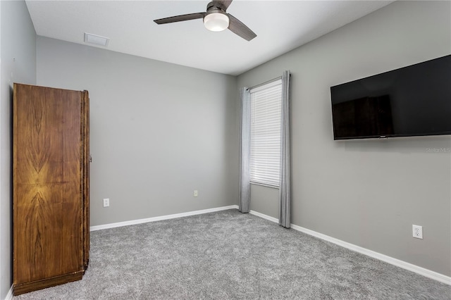 carpeted empty room featuring ceiling fan and baseboards