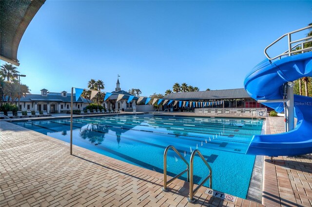 pool featuring a water slide and a patio