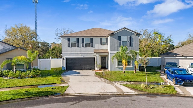 traditional-style home featuring stucco siding, concrete driveway, an attached garage, a front yard, and fence