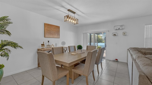 dining room featuring baseboards, a notable chandelier, and light tile patterned flooring