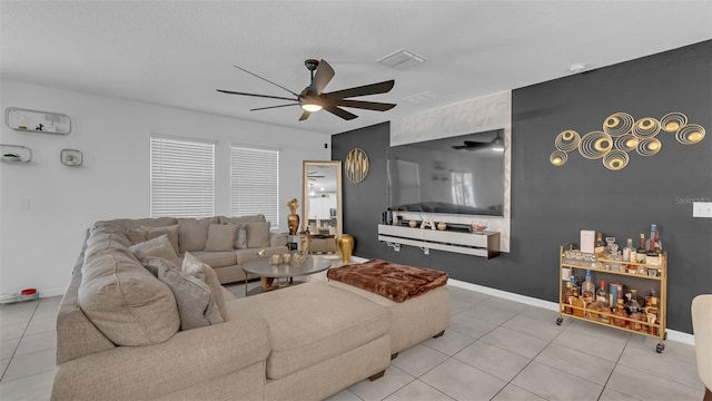 living area featuring ceiling fan, visible vents, baseboards, and tile patterned floors