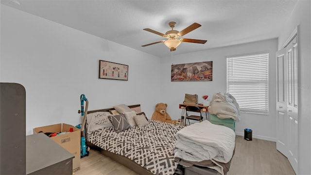 bedroom featuring a ceiling fan, a closet, baseboards, and wood finished floors