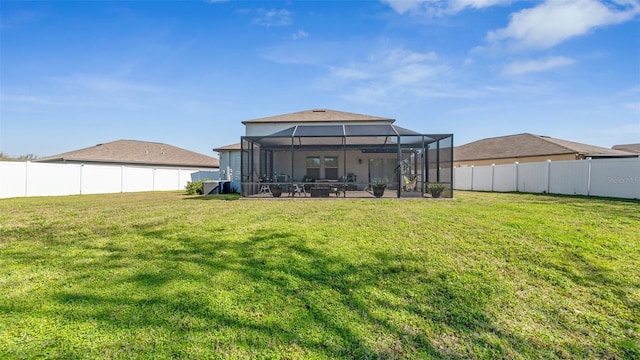 rear view of house with a lanai, a fenced backyard, and a yard