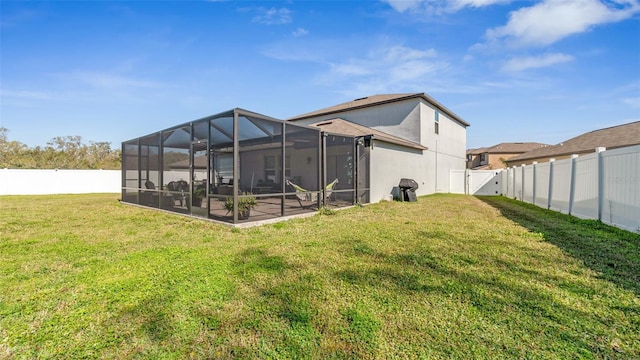 back of house featuring glass enclosure, a lawn, a fenced backyard, and stucco siding