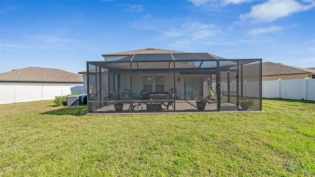 back of house featuring glass enclosure, a fenced backyard, a patio, and a lawn