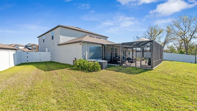 rear view of house with a yard, a fenced backyard, a gate, and stucco siding