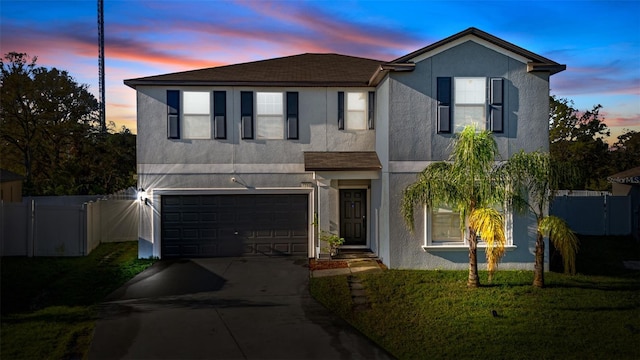 traditional-style home featuring an attached garage, fence, concrete driveway, and stucco siding