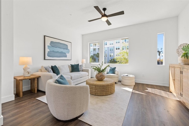 living area featuring dark wood-type flooring, ceiling fan, and baseboards