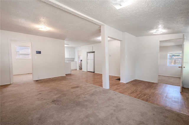 1800 27th Ave N, Saint Petersburg, FL 33713 - basement with light wood-type flooring, freestanding refrigerator, light colored carpet, and a textured ceiling