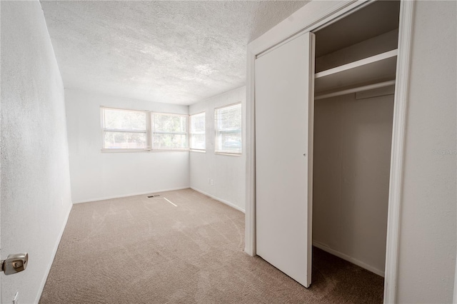 1800 27th Ave N, Saint Petersburg, FL 33713 - unfurnished bedroom featuring a textured ceiling, carpet floors, a closet, and a textured wall