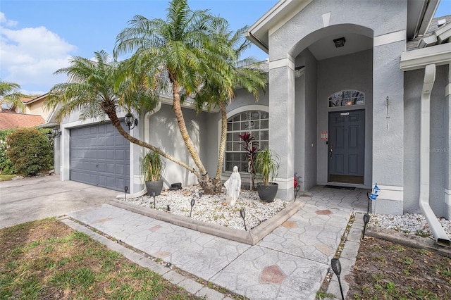 property entrance featuring concrete driveway, an attached garage, and stucco siding