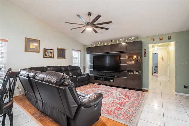 living room with lofted ceiling, light tile patterned floors, ceiling fan, and baseboards