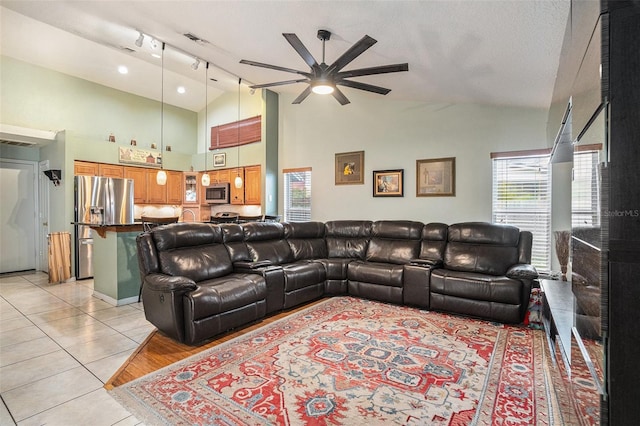 living area featuring light tile patterned floors, a ceiling fan, visible vents, and high vaulted ceiling