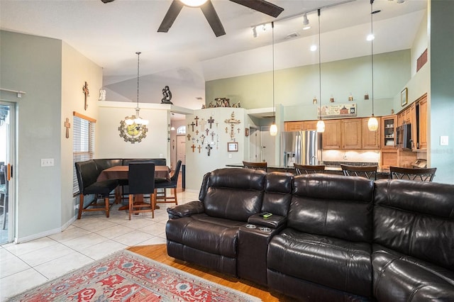 living area with light tile patterned floors, visible vents, baseboards, high vaulted ceiling, and ceiling fan with notable chandelier