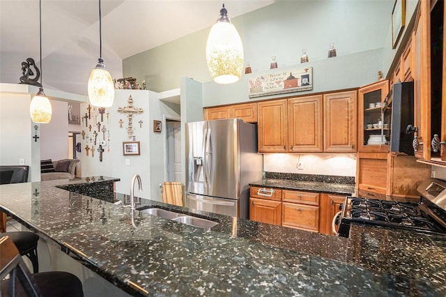 kitchen with appliances with stainless steel finishes, dark stone counters, brown cabinetry, and a sink