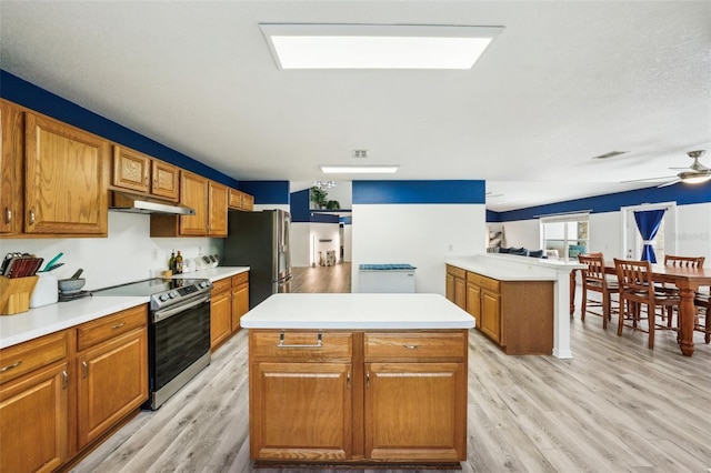 kitchen with stainless steel appliances, brown cabinets, and under cabinet range hood