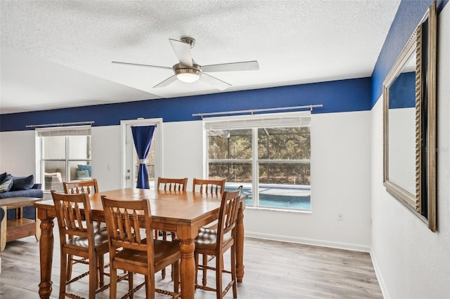 dining room featuring ceiling fan, a textured ceiling, baseboards, and wood finished floors