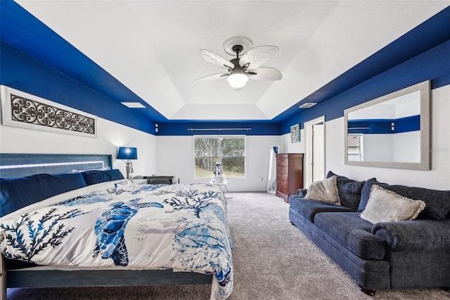 bedroom with carpet, a raised ceiling, and a ceiling fan