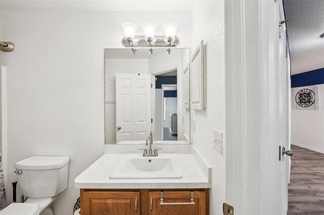 bathroom featuring wood finished floors, vanity, and toilet