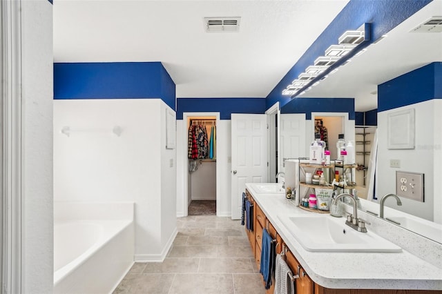 bathroom featuring a garden tub, visible vents, and a sink