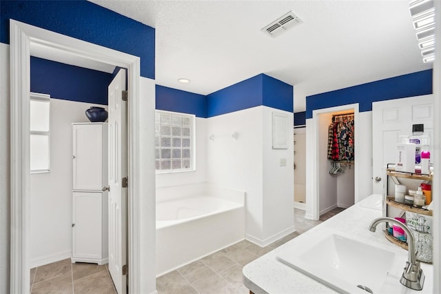 bathroom featuring visible vents, a sink, baseboards, and a bath