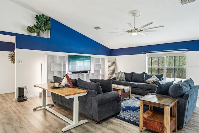 living area with lofted ceiling, light wood-style floors, and visible vents