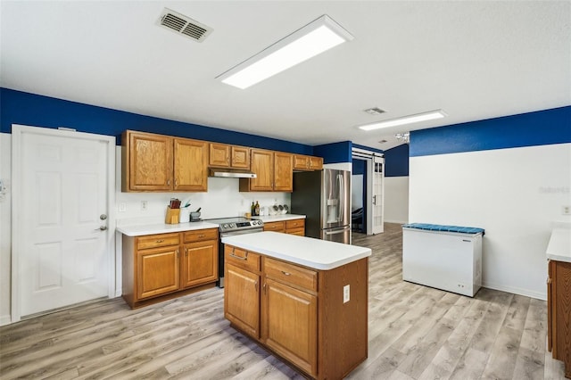 kitchen featuring appliances with stainless steel finishes, brown cabinetry, visible vents, and under cabinet range hood