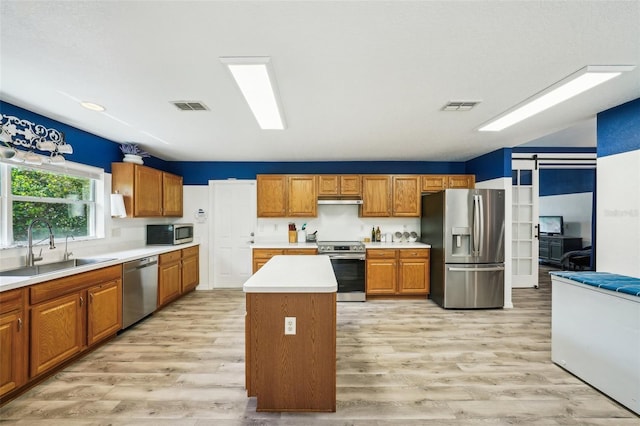 kitchen featuring a barn door, visible vents, appliances with stainless steel finishes, and a sink