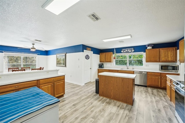 kitchen with stainless steel appliances, light wood-type flooring, light countertops, and visible vents