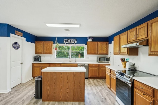 kitchen featuring light wood finished floors, light countertops, appliances with stainless steel finishes, a sink, and under cabinet range hood