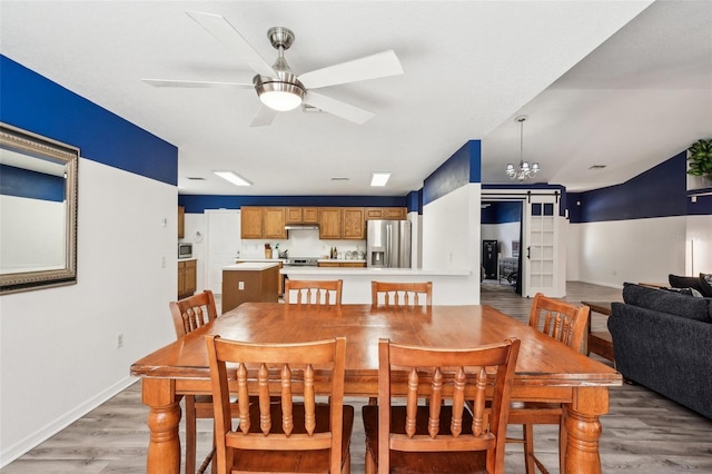 dining space featuring baseboards, light wood finished floors, and ceiling fan with notable chandelier