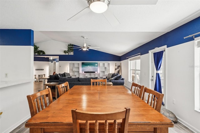 dining area featuring a ceiling fan, lofted ceiling, baseboards, and wood finished floors