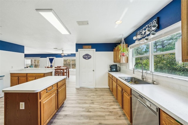 kitchen featuring brown cabinets, light countertops, light wood-style flooring, a sink, and dishwasher