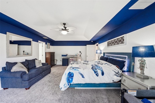 bedroom featuring a ceiling fan, visible vents, a tray ceiling, and carpet flooring