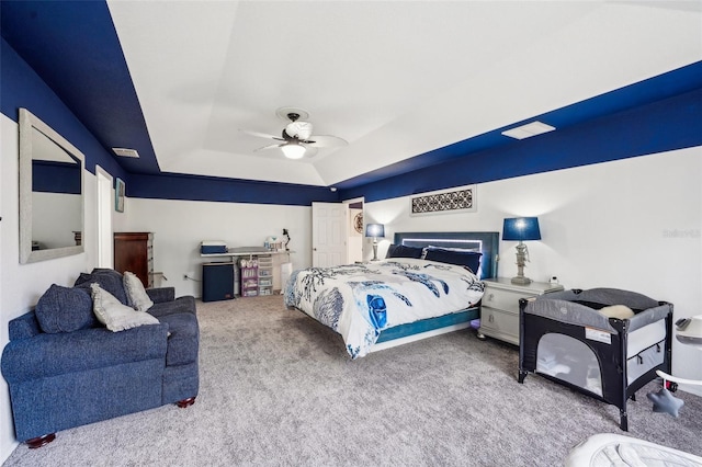 bedroom featuring carpet, visible vents, a raised ceiling, and a ceiling fan