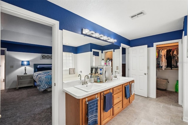 bathroom with double vanity, a sink, visible vents, and connected bathroom